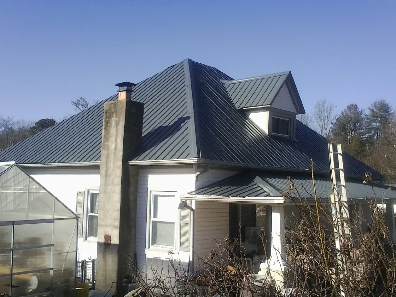 Dark blue standing seam metal roof on a white farmhouse with dormer — Slate & Tile Roof Repair by Roofing Brothers in Chicago