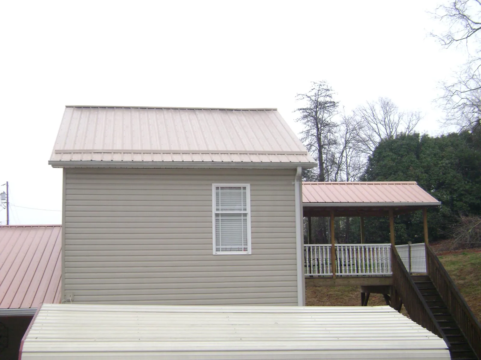 Tan metal roofs on a two story addition and attached porch, from a Roof Replacement job in Chicago