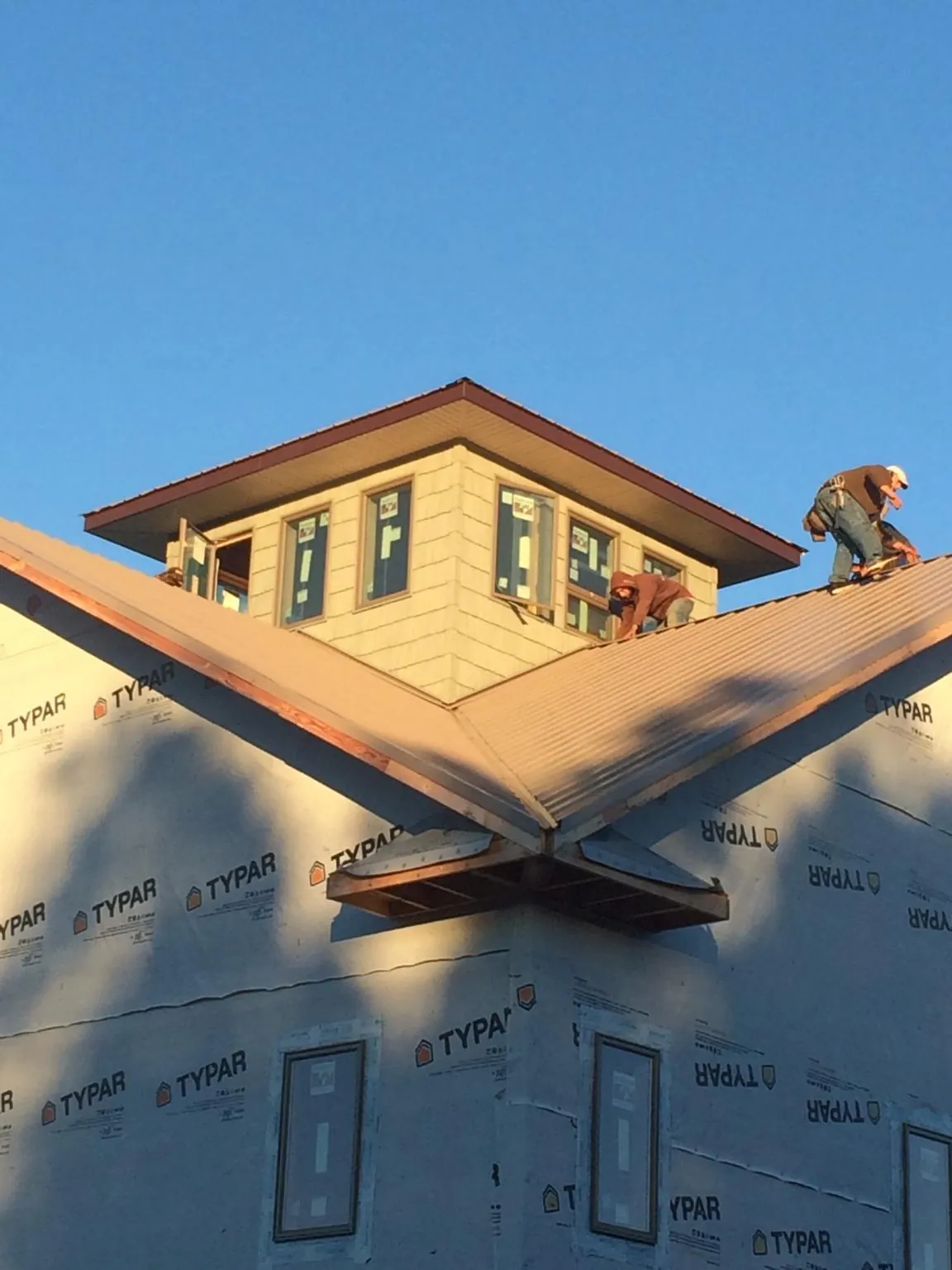 Roofers working around a rooftop cupola on a new metal roof at sunset — Roof Waterproofing in Chicago by Roofing Brothers
